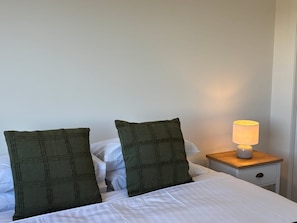 Ein Bett mit zwei Kissen und einem Nachttisch mit einer Lampe.