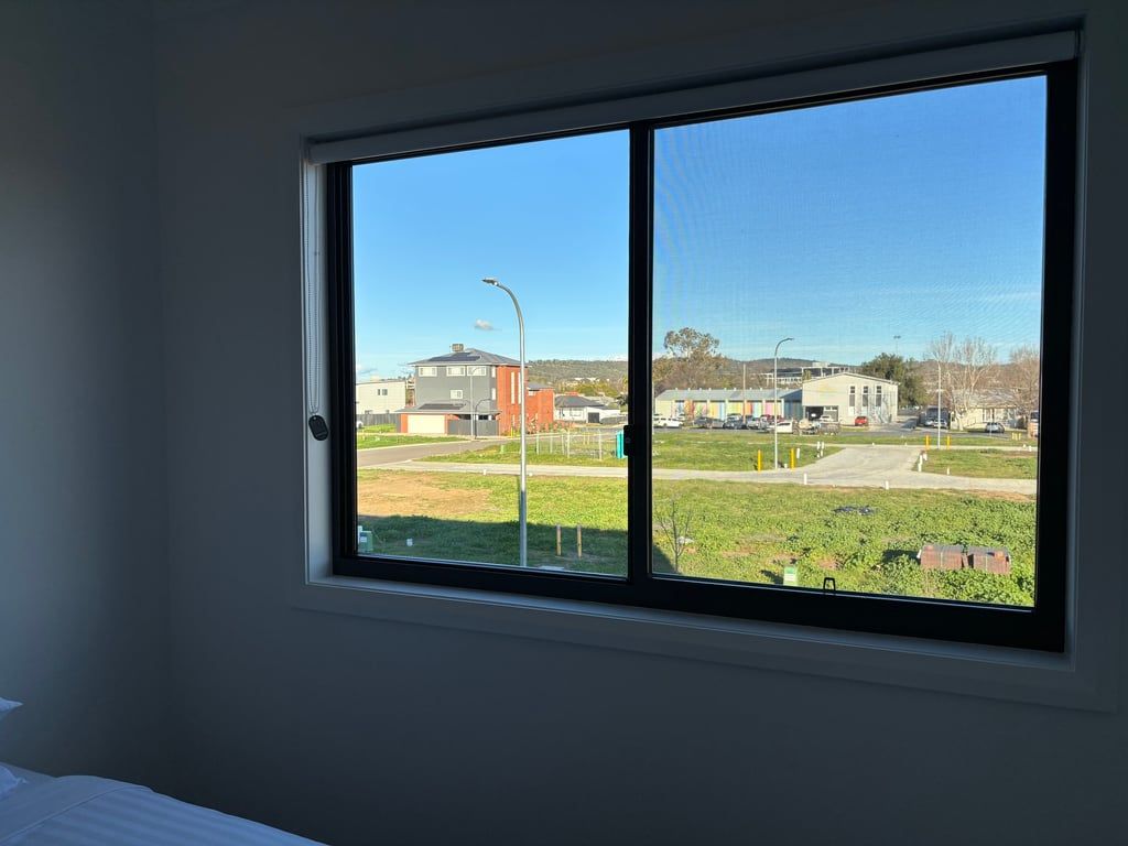A room with a large window overlooking a parking area and buildings.