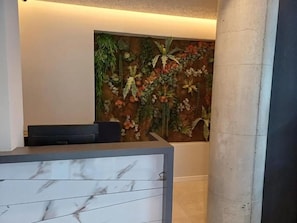 A reception area with a marble counter and a wall decorated with a nature-themed mural. - Oxygen Boutique Hotel Tirana (Tirana)