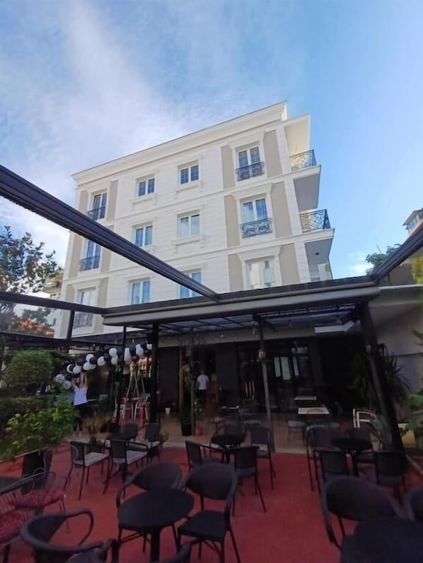 An outdoor seating area with tables and chairs, a glass enclosure, and a building in the background. - Oxygen Boutique Hotel Tirana (Tirana)