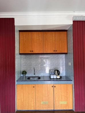 A compact kitchen with wooden cabinets, a tiled backsplash, and a stainless steel sink. - Lilla Hilltop Retreats (Janda Baik)