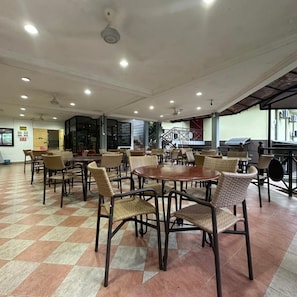 A spacious indoor dining area with multiple tables and chairs, a tiled floor, and a ceiling with recessed lighting. - Lilla Hilltop Retreats (Janda Baik)