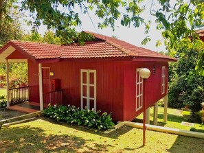 Un edificio rosso con un portico, una porta e una finestra.