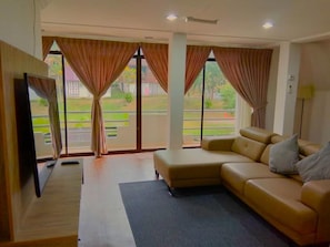 Un salon avec un canapé, un téléviseur à écran plat et une vue sur l’extérieur.