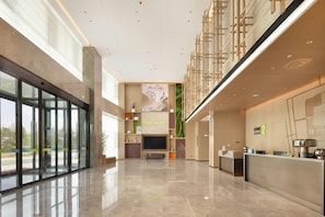 A spacious lobby with a reception desk, a large flat-screen TV, and a mural of a Ferris wheel. - Home2 Suites by Hilton Liaocheng Dongchang (Liaocheng)