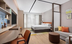 Una habitación de hotel moderna con cama, escritorio, sofá y zona de comedor.