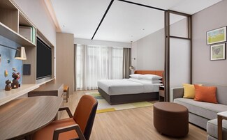Una habitación de hotel moderna con cama, escritorio, sofá y zona de comedor.