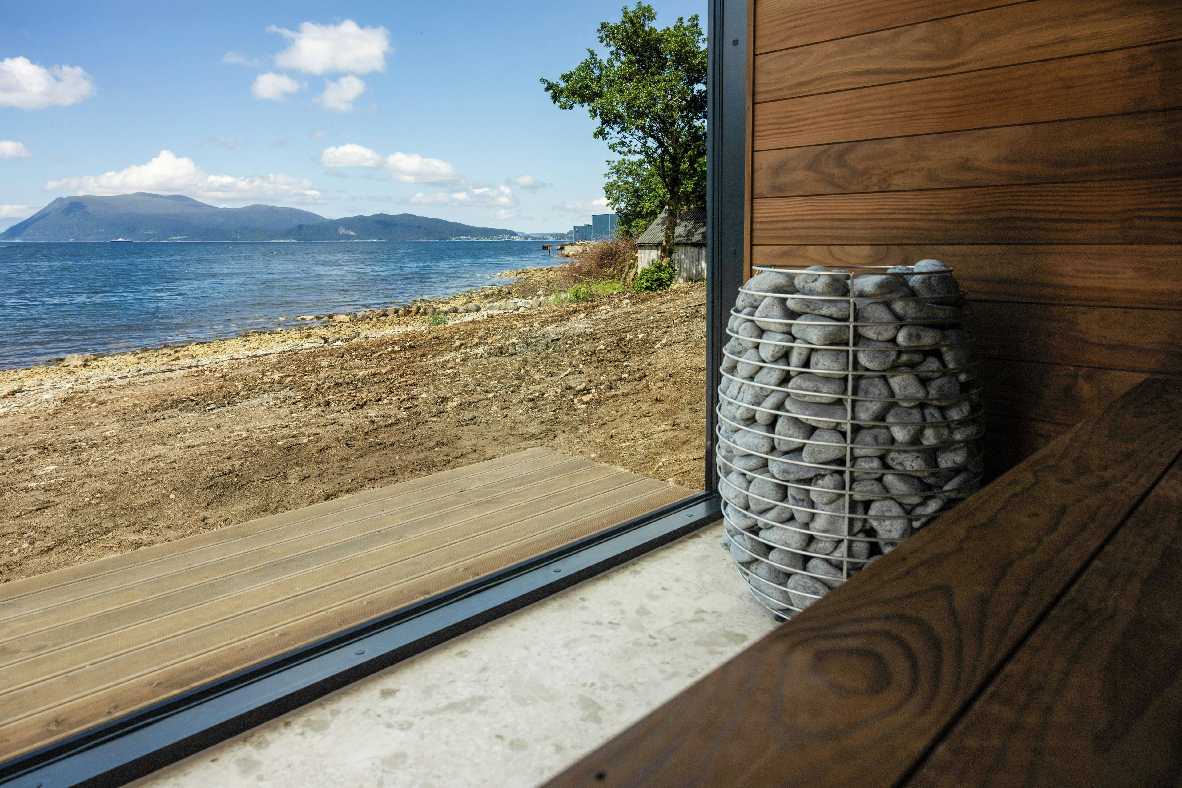 A wooden bench with a stone wall and a view of a beach and ocean.