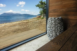 Un banco de madera con un muro de piedra y vista a una playa y al océano.