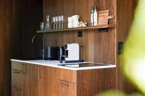 Cozinha moderna com armários de madeira, máquina de café integrada e bancada com diversos utensílios de cozinha.