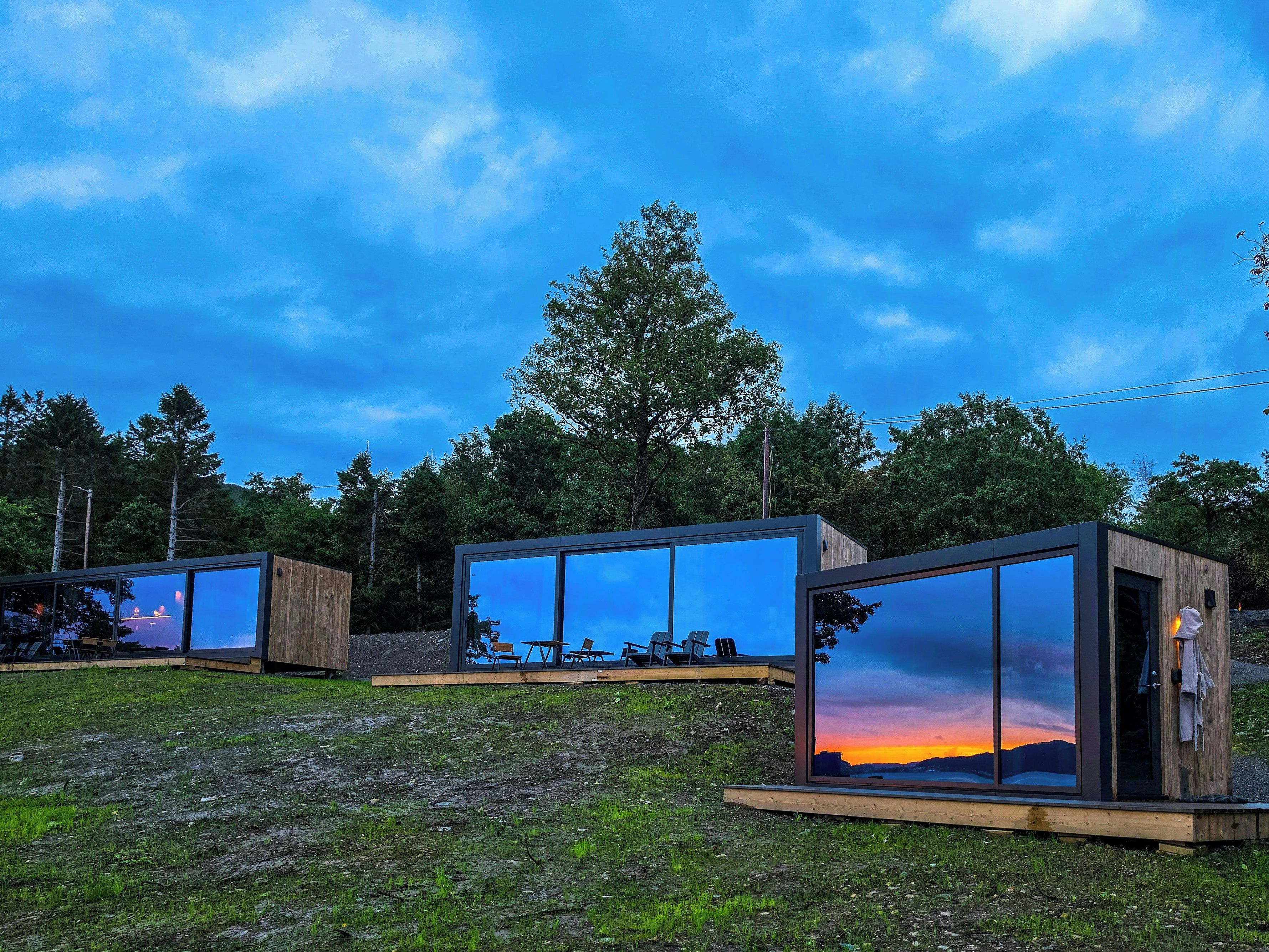 Eine moderne Außenarchitektur mit Glaswänden, einer Holzterrasse und einer Sitzgelegenheit.
