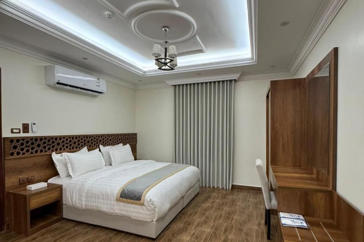 A hotel room with a skylight, a bed, a desk, and a wooden floor.