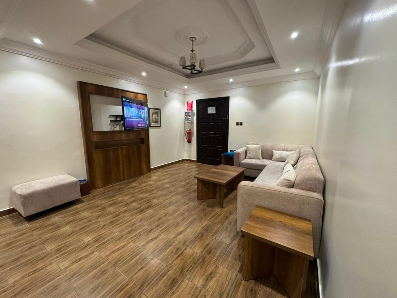 A room with a wooden floor, a sofa, a coffee table, and a television.