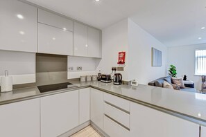 A modern kitchen with white cabinets, a built-in oven, and a coffee maker. - St Martins 2 Bedroom and 2 Bathroom Apt. 5 - South Ruislip (Ruislip)