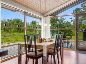An open-plan dining area with a wooden table and chairs, large windows, and a view of greenery. - "Thiokk" - 1.5km from the sea by Interhome (Ålbæk)
