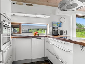 A modern kitchen with white cabinetry, a built-in oven, and a coffee machine. - "Thiokk" - 1.5km from the sea by Interhome (Ålbæk)
