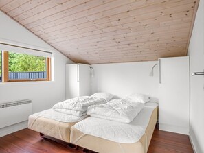 A bedroom with a wooden ceiling, a window with a view of greenery, a bed with white bedding, and a white wardrobe. - "Thiokk" - 1.5km from the sea by Interhome (Ålbæk)