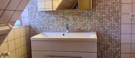 A bathroom with a white sink, a mirror, and tiled walls.