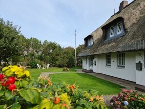 A traditional thatched-roof house with a well-maintained lawn and outdoor seating area. - Holiday Home in Nieblum With Swimming Pool (Nieblum)