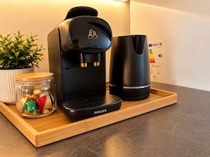 Een koffiezetapparaat, een mok en een potje met lekkernijen op een houten dienblad.