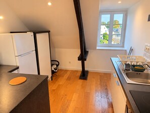 Een kleine keuken met een inbouwoven, een spoelbak en een raam met uitzicht.