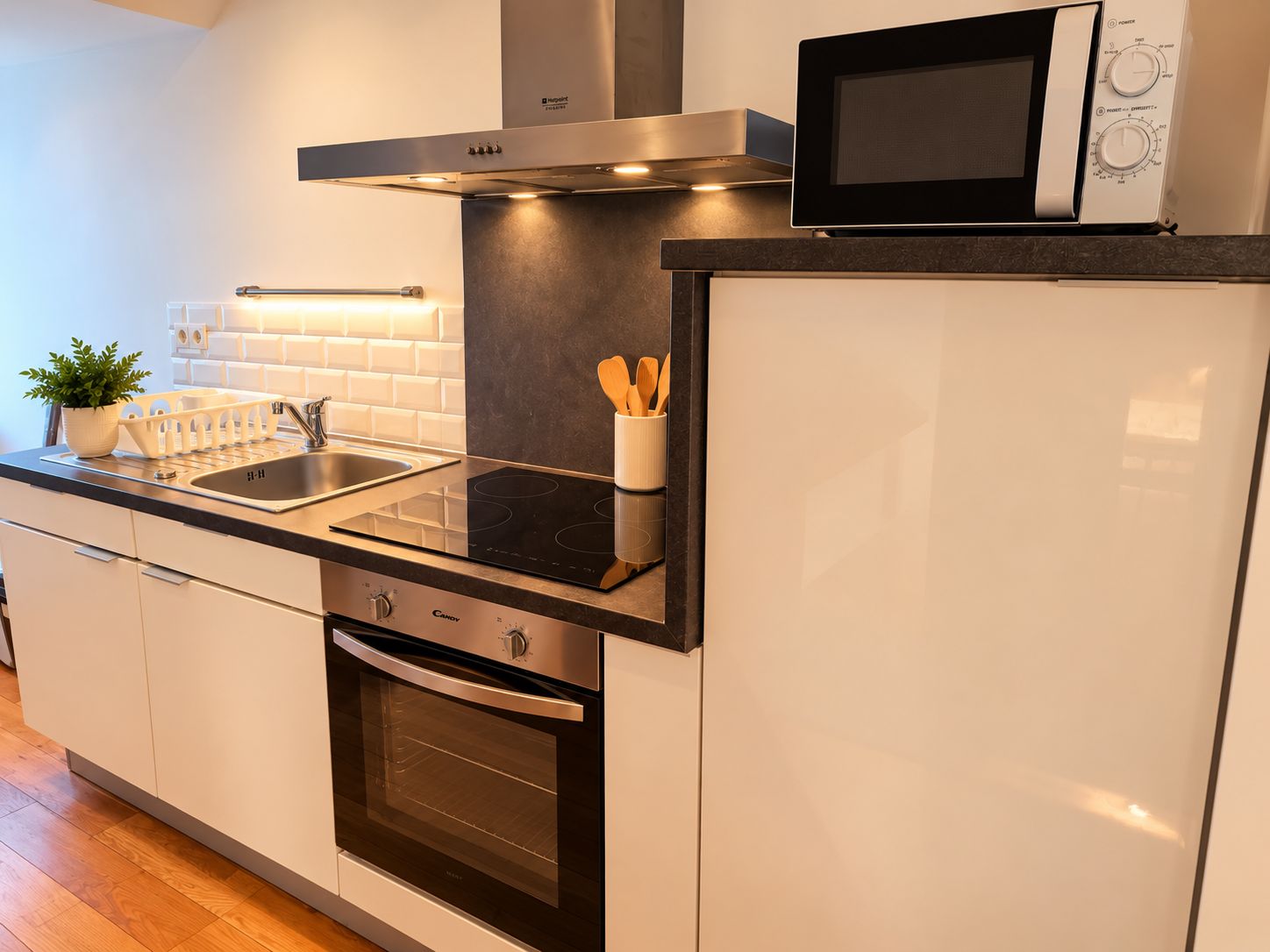 Una cocina moderna con horno empotrado, microondas y campana extractora de acero inoxidable.