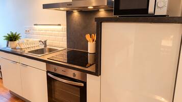 Una cocina moderna con horno empotrado, microondas y campana extractora de acero inoxidable.