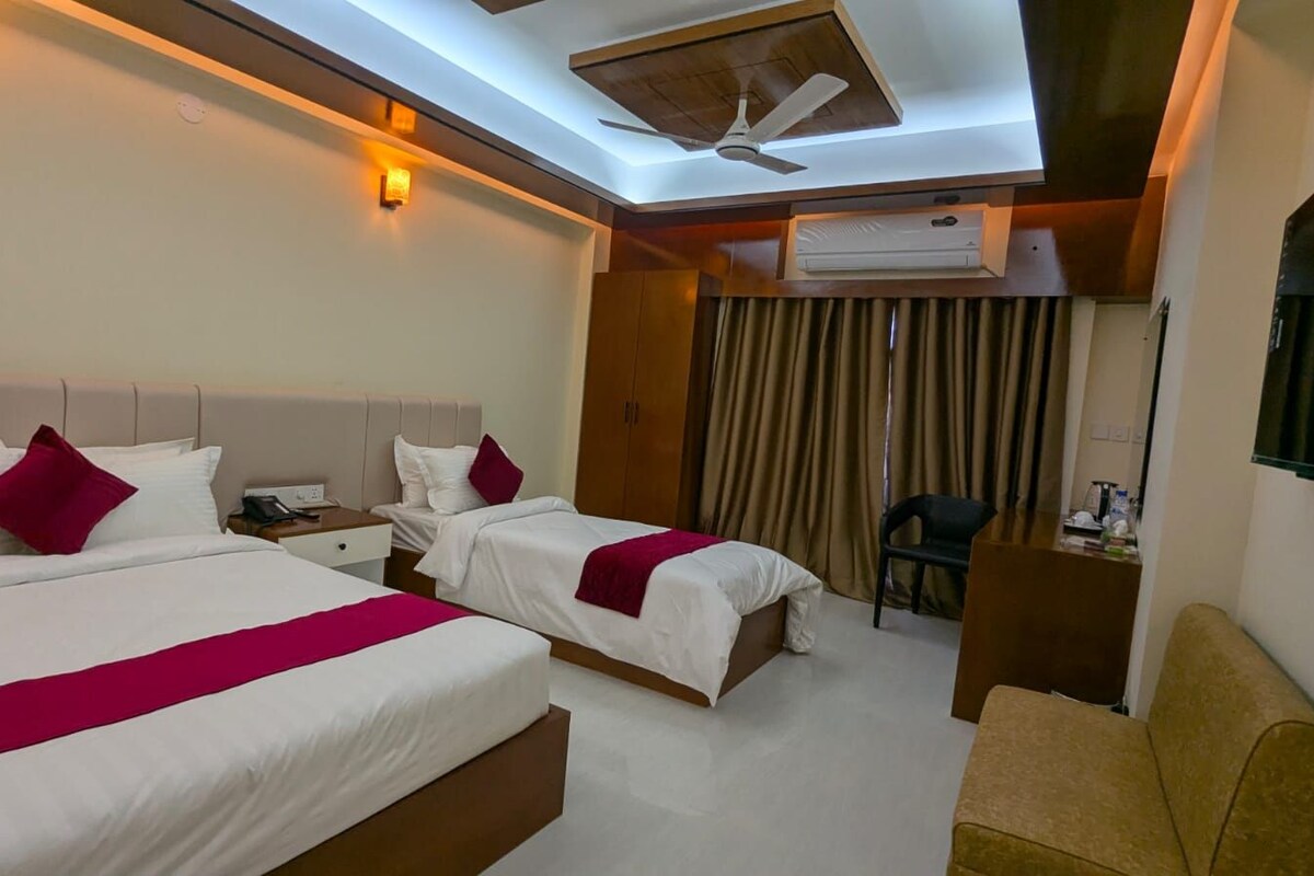 Une chambre d’hôtel avec deux lits, un ventilateur de plafond, un appareil de climatisation, un bureau et une chaise.