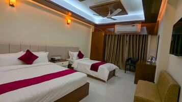 A hotel room with two beds, a ceiling fan, an air conditioning unit, a desk, and a chair.