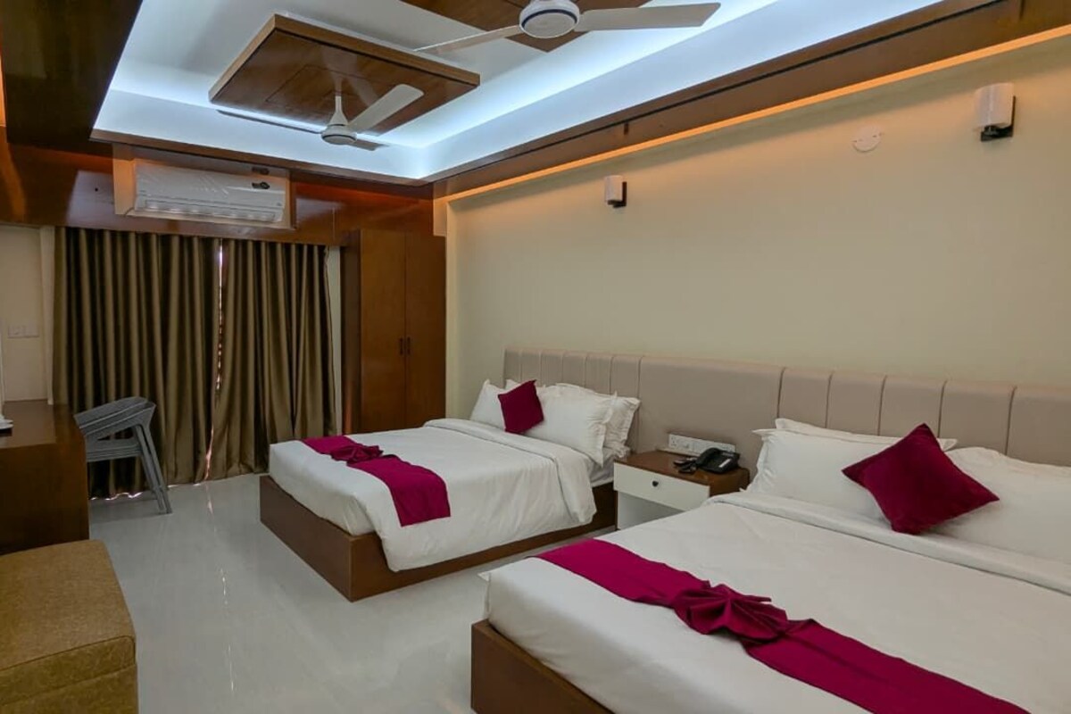 Une chambre d’hôtel avec deux lits, un ventilateur de plafond, un appareil de climatisation, un bureau avec une chaise et un téléviseur.