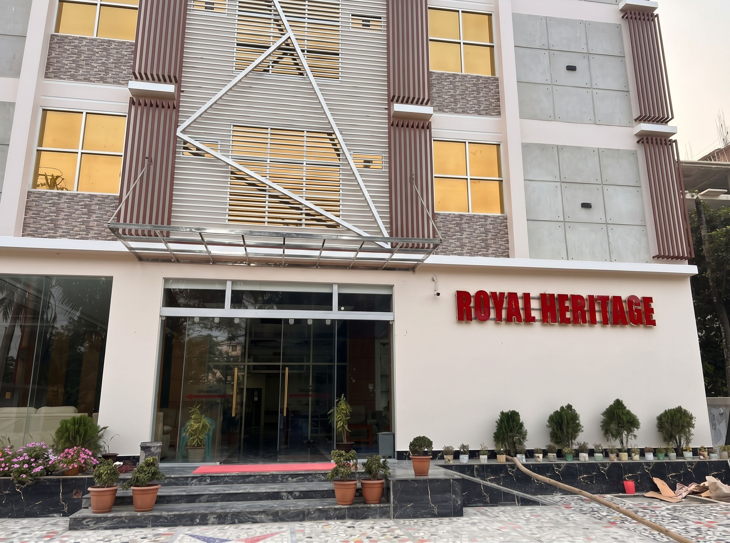 A building with a modern facade, a prominent 'ROYAL HERITAGE' sign, and a series of potted plants in front.