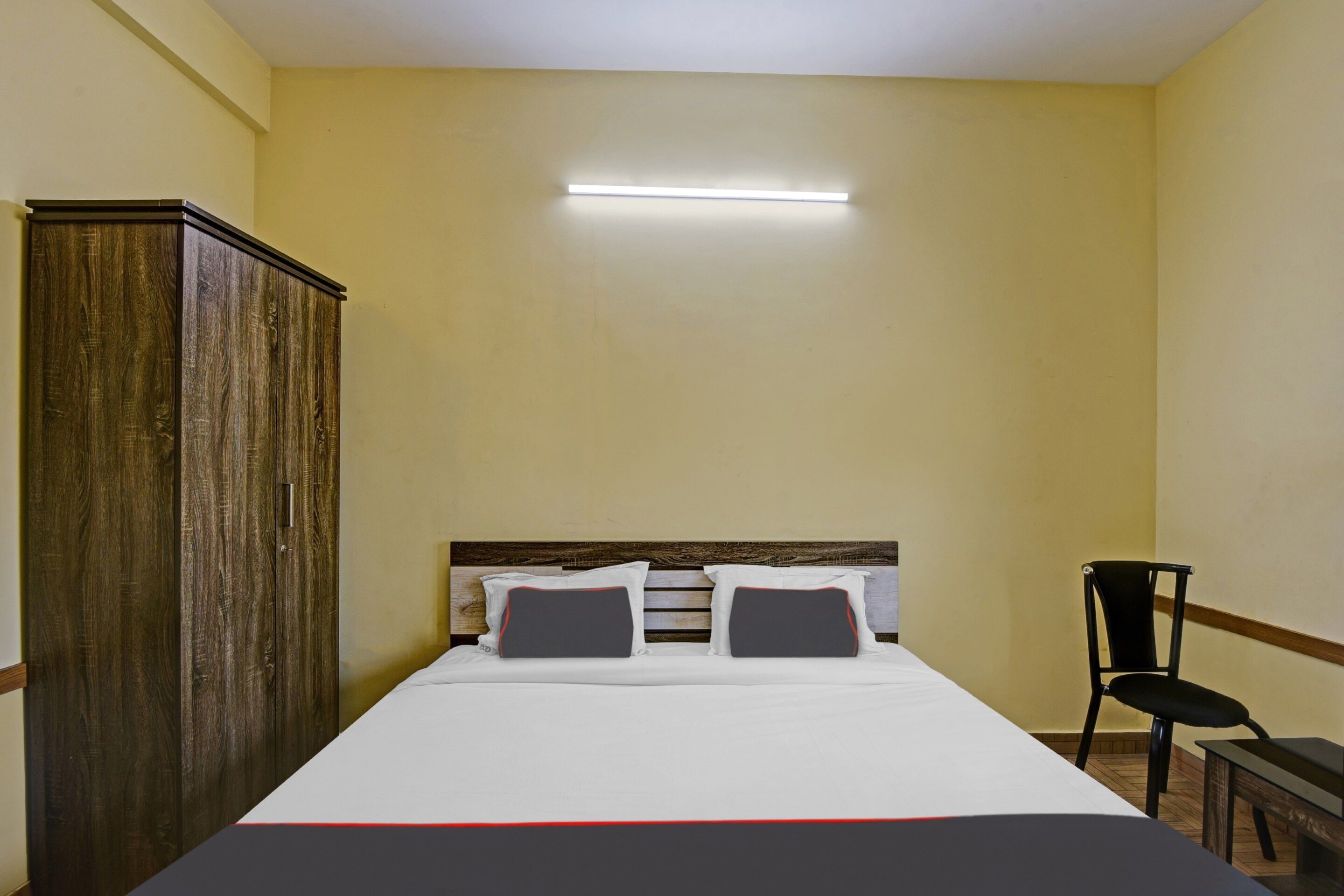 Una habitación de hotel con una cama, un armario, una silla y una mesita de noche.
