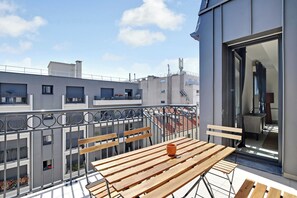 A balcony with wooden benches and a table, overlooking a cityscape with modern buildings. - Elegant Appt - 3bdr/8p - Near Paris & La Defense (Suresnes)