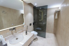 Une salle de bain moderne avec un grand miroir, un lavabo doté d’un receveur texturé et une douche à l’italienne.
