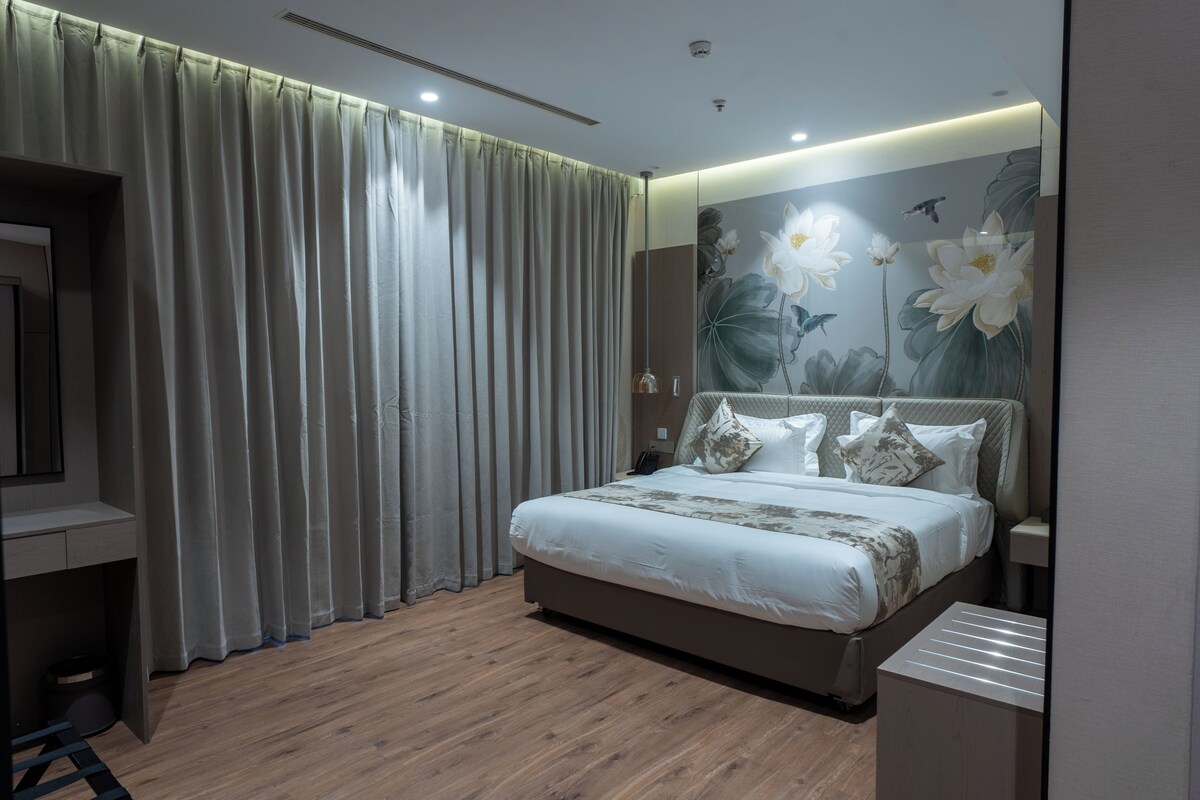 Une chambre moderne avec un grand lit, un plancher en bois et une fresque murale à motifs floraux.