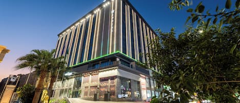 A modern building with a prominent vertical design, a glass facade, and a well-lit entrance.