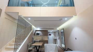 Ein modernes Interieur mit Treppe, Essbereich, Küche und einer oberen Ebene mit Glasgeländer.