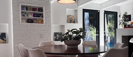 A modern dining area with a round table, white chairs, and a red pendant light.