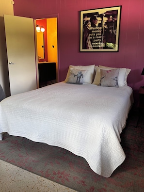 A room with a bed, a door, a mirror, and a poster on the wall. - Mid-century designer home with pool and grill in plantation (Plantation)