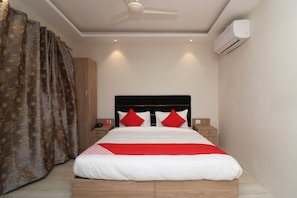 A hotel room with a bed, a ceiling fan, an air conditioning unit, and a nightstand with a phone. - Hotel O Madhurapuri (Calicut)