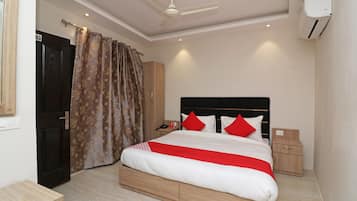 A bedroom with a bed, a nightstand, a wardrobe, a ceiling fan, and an air conditioning unit.