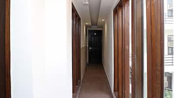 A narrow hallway with wooden doors and a carpeted floor, leading to a dark door at the end.