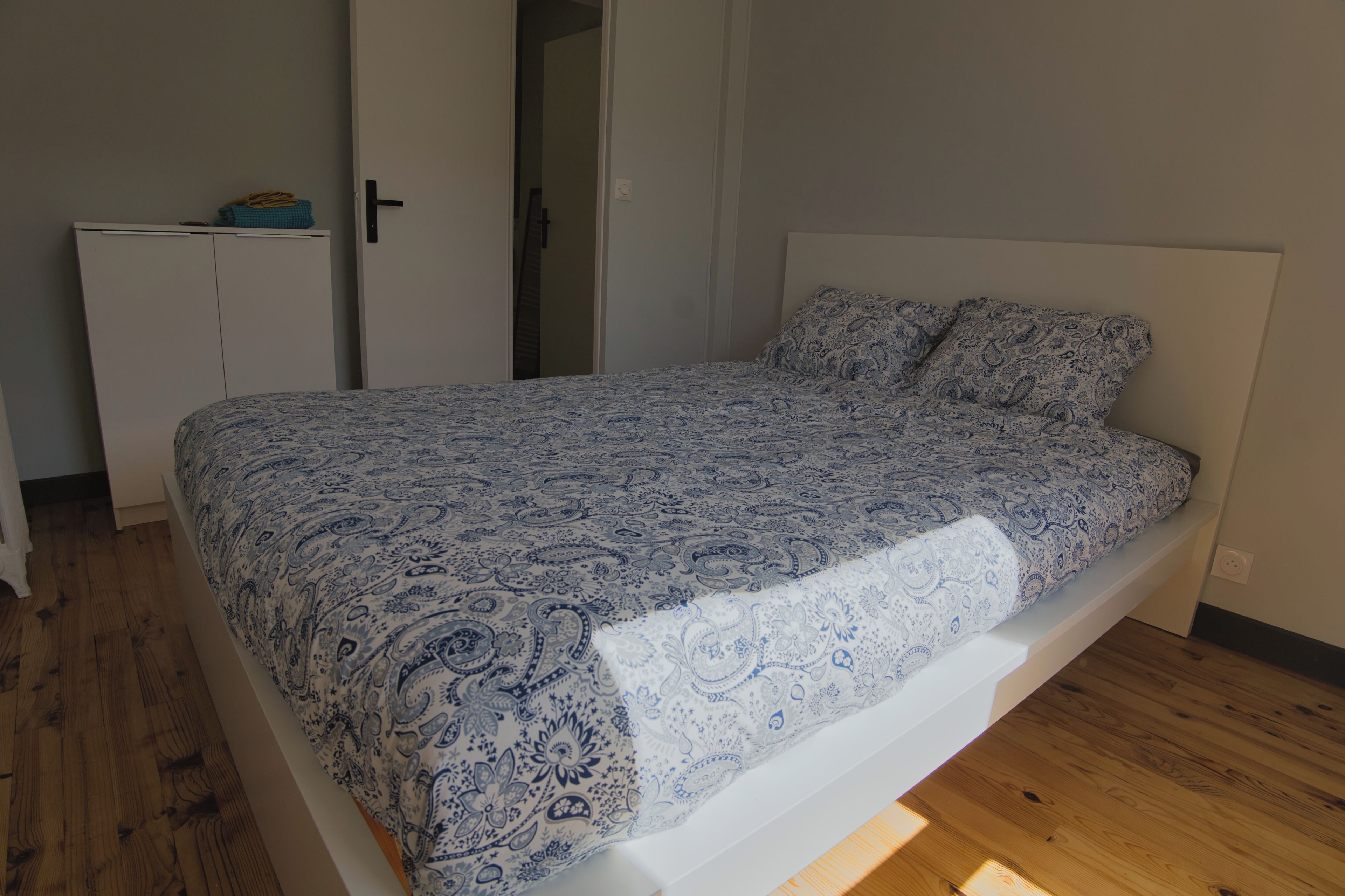 Une chambre à coucher comprenant un lit, une armoire et une porte donnant sur une autre pièce.