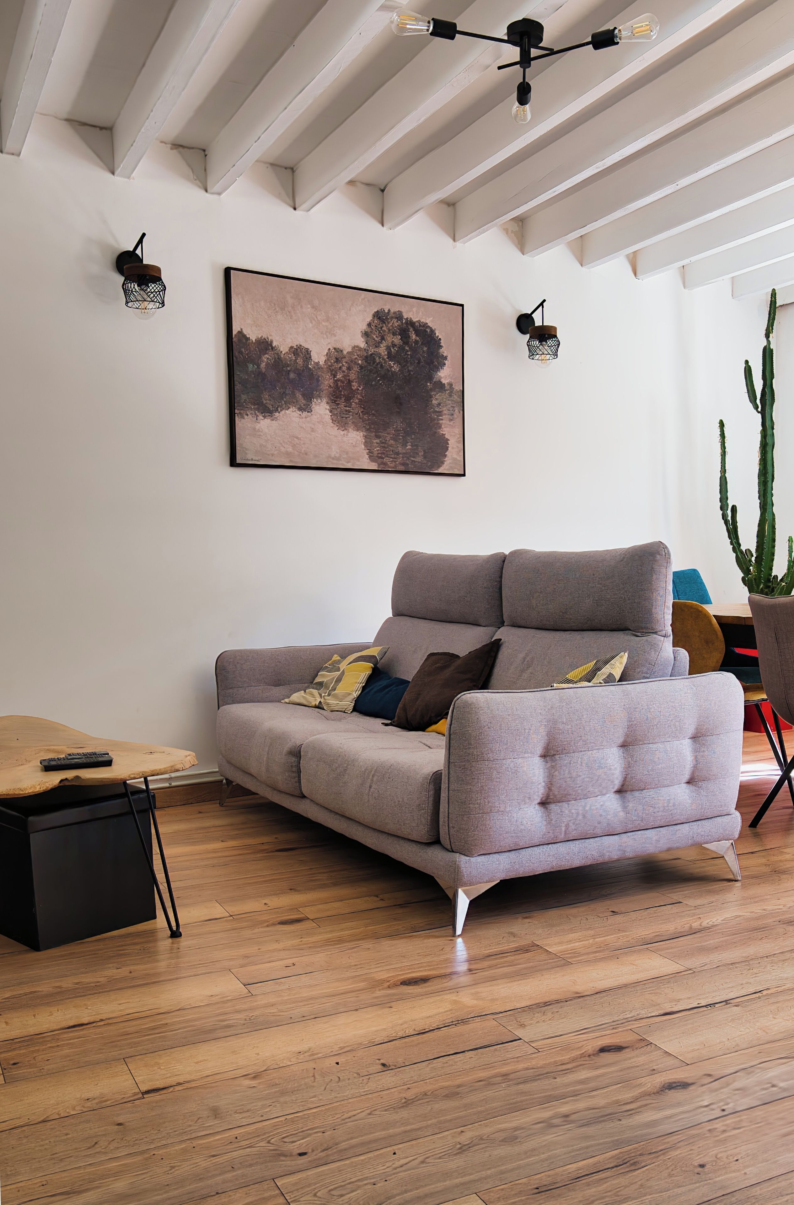 A modern living room with a grey sofa, a wooden coffee table, and a cactus plant.