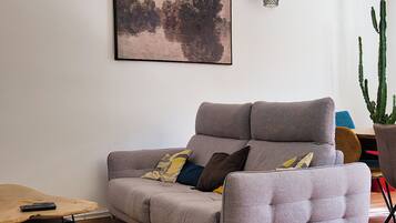 A modern living room with a grey sofa, a wooden coffee table, and a cactus plant.
