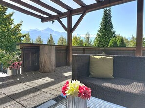 An outdoor seating area with a view of mountains, a wooden pergola, and a table with a vase of flowers. - Nice apartment for 6 people with WIFI, TV, patio and pets allowed (Zell Am See)