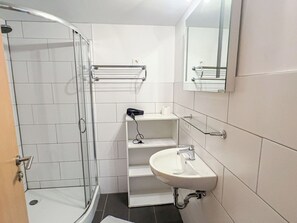 Ein Badezimmer mit Dusche, Waschbecken und Spiegel.