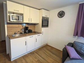 A compact kitchenette with a microwave, oven, and coffee maker. - Cosy apartment for 4 people with WIFI, TV, patio and pets allowed (Zell Am See)
