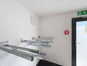 Escadaria com corrimãos de metal, alarme de incêndio e placa de saída de emergência.