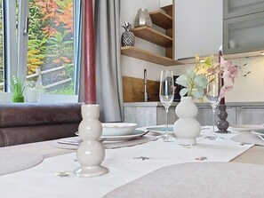 Un coin repas avec une table dressée pour deux personnes, agrémentée d’assiettes blanches, de verres transparents et d’un chandelier blanc.